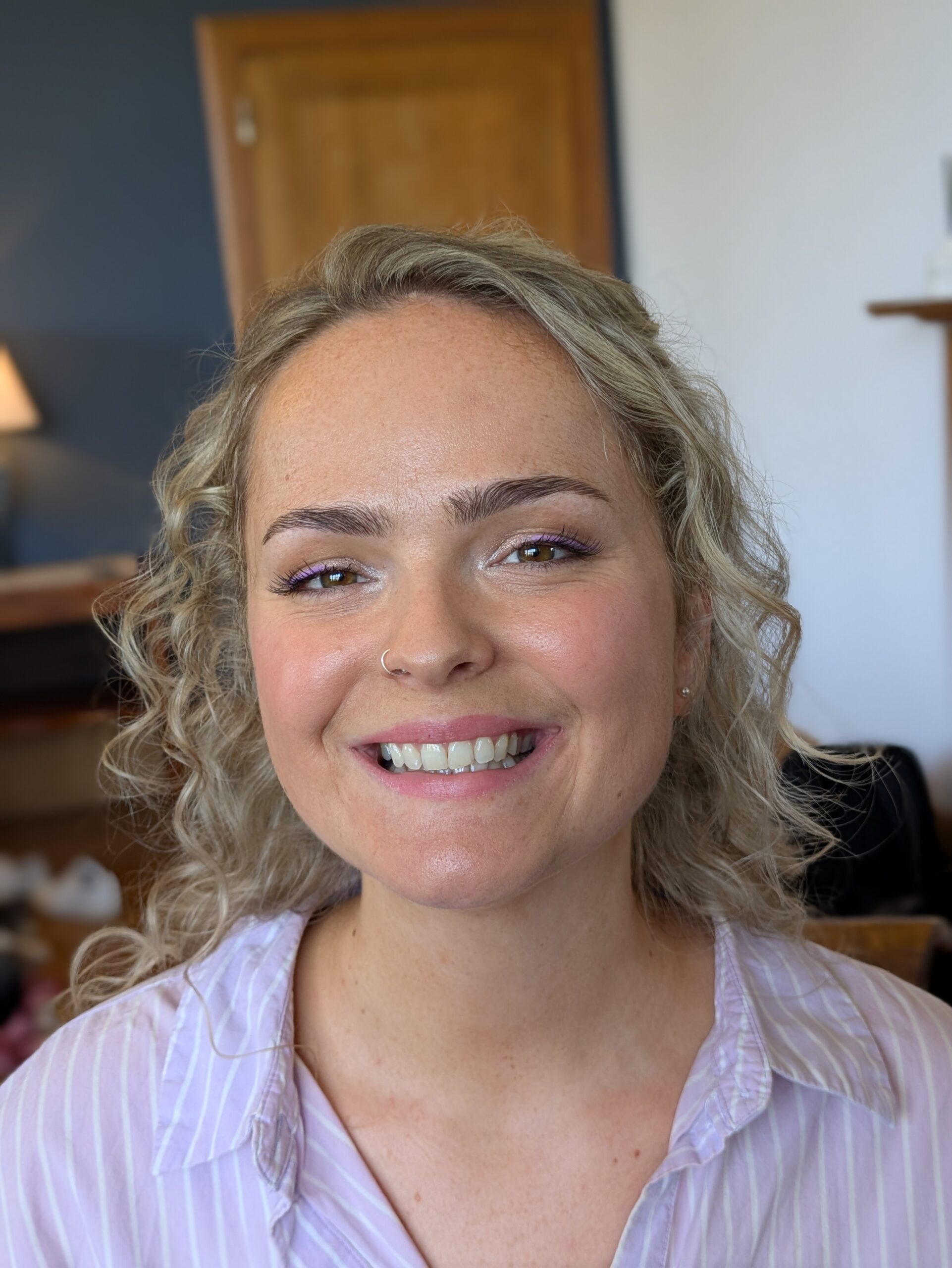 a blonde smiling bride wearing purple eyeliner on her same sex wedding day at coombe lodge