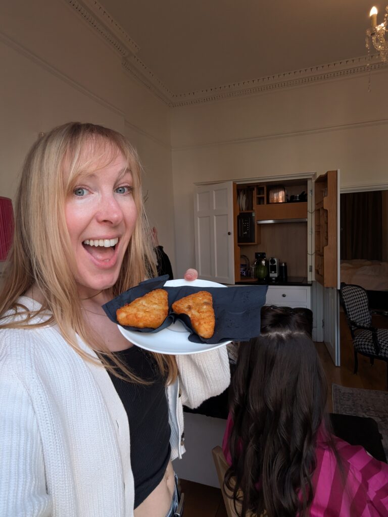 wedding hair and makeup artist in Bristol. Smiling, holding a plate of hash browns at The Square Bar
